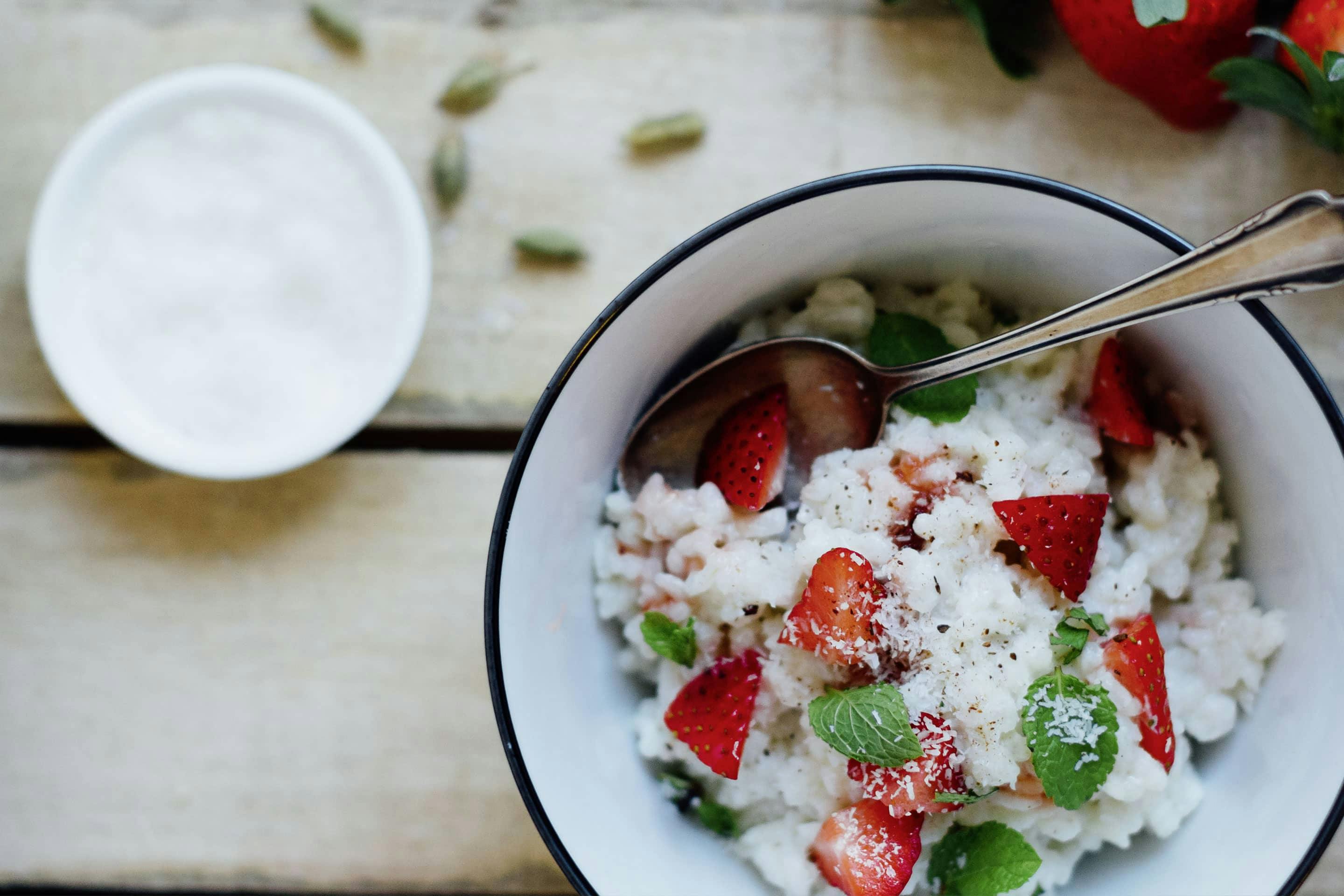 Kokosmilchreis mit Cardamom und Erdbeeren in einer weißen Schüssel mit blauem Rand