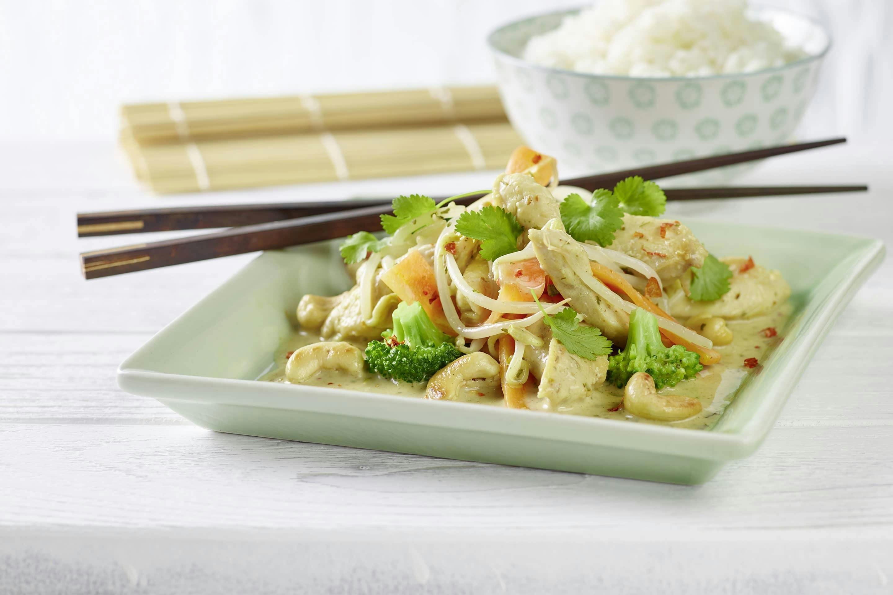 Chicken Thai mit asiatischen Kräutern, Broccoli und frischen Sojasprossen auf einem eckigen Teller mit Essstäbchen