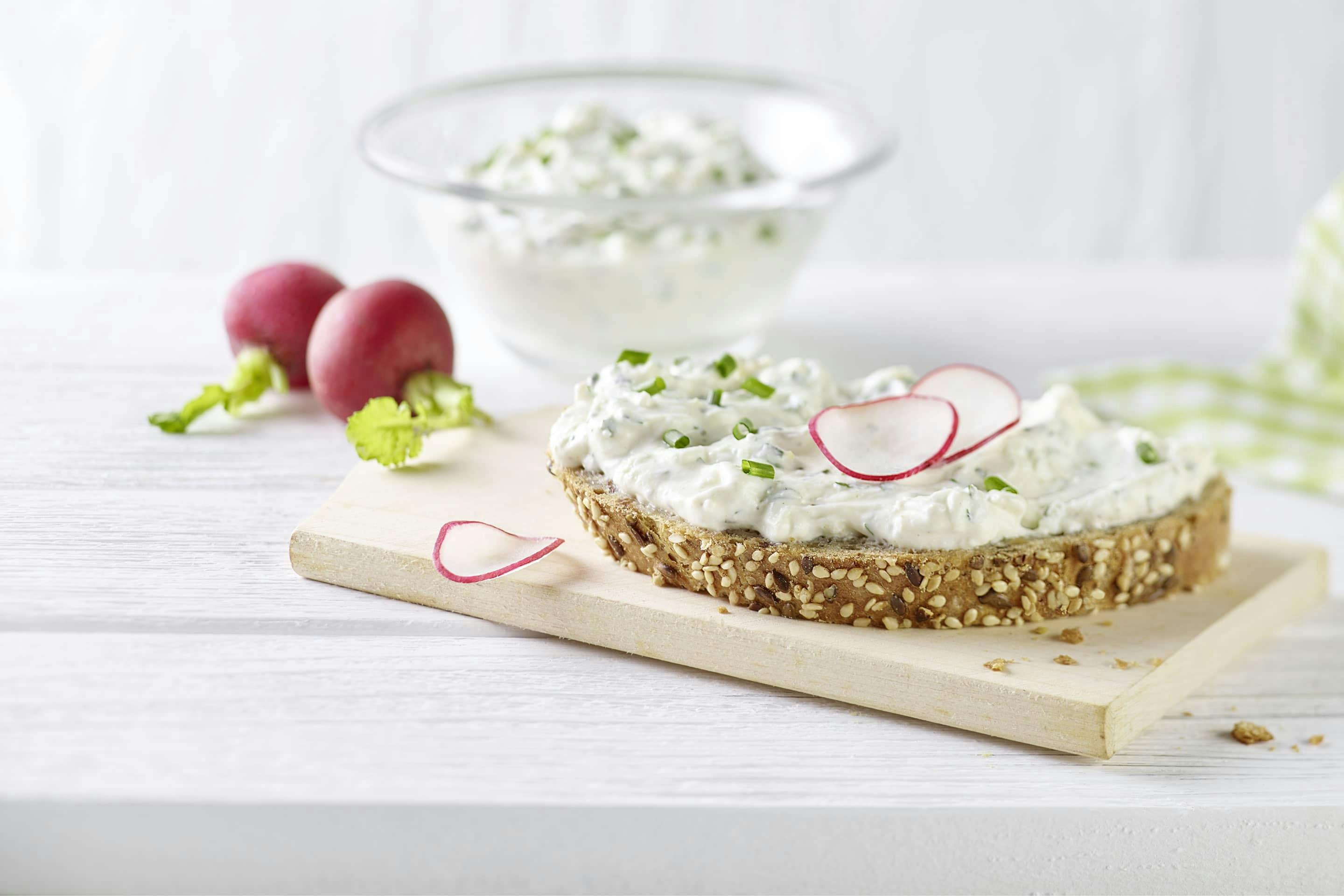 Hüttenkäse mit Kräutern der Provence auf Mehrkornbrot, garniert mit Radieschen-Scheiben