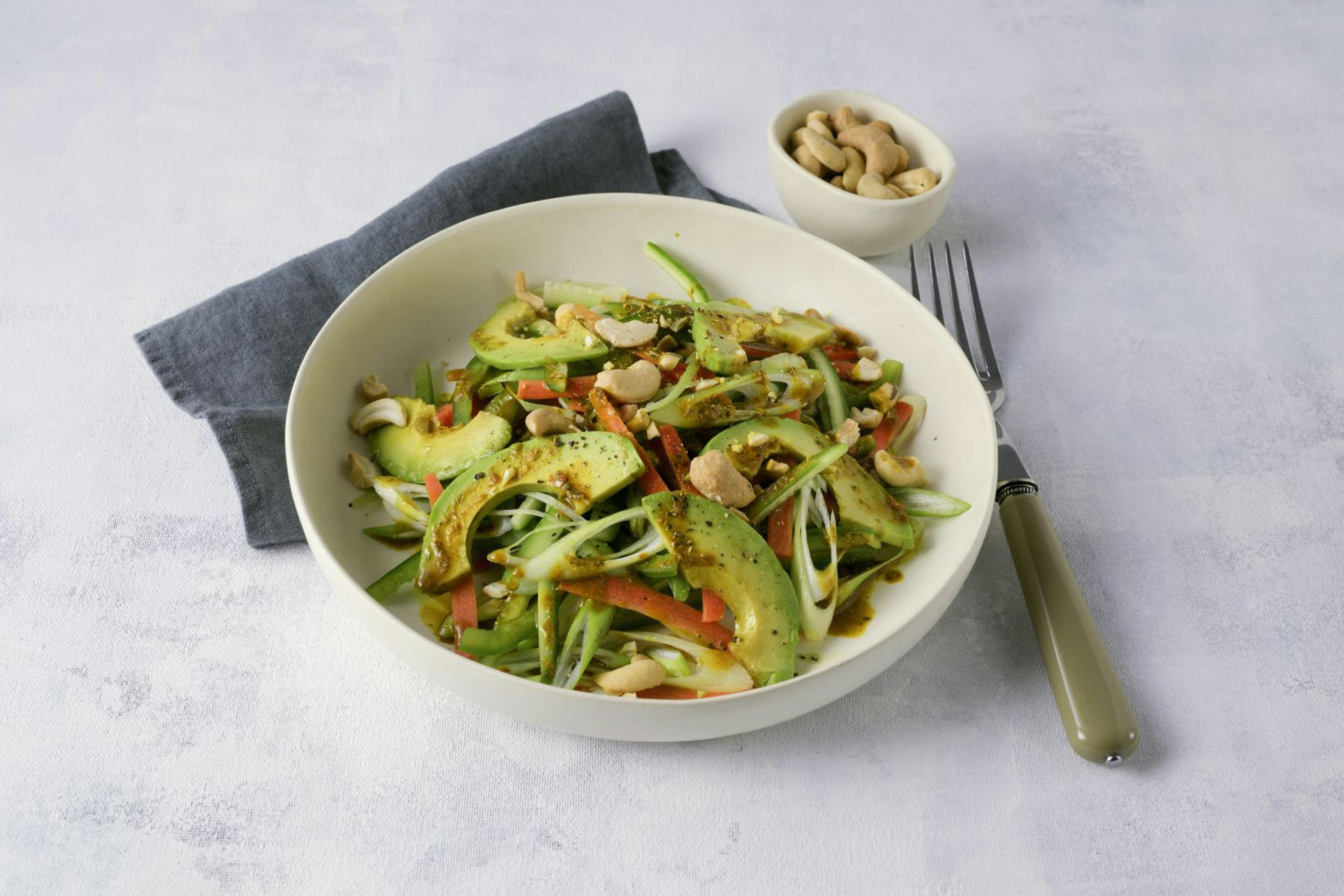 Asia-Salat mit gebratener Avocado und Cashewkernen in einer cremefarbenen Schale