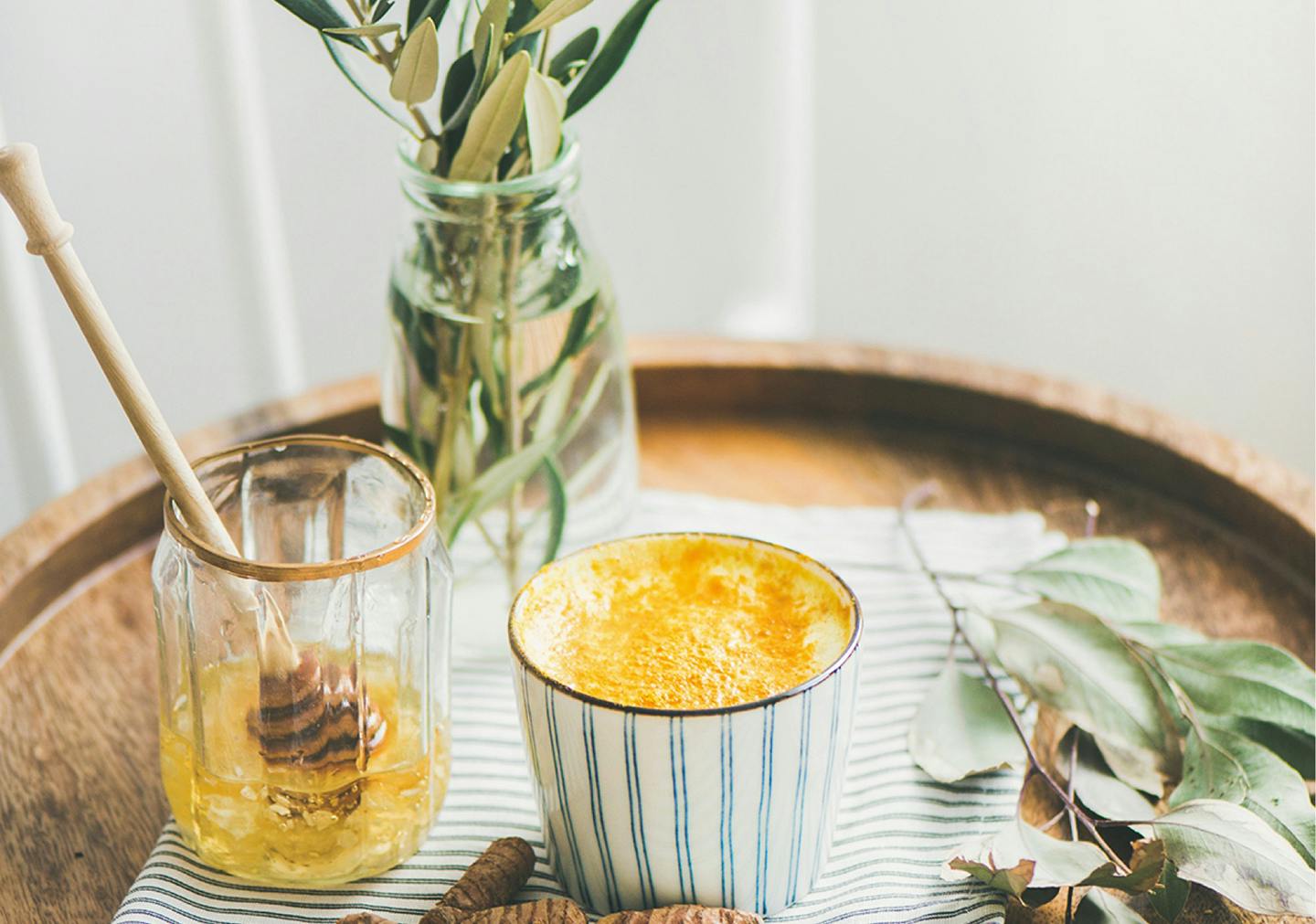 Tasse Golden Milk neben einem Honigglas