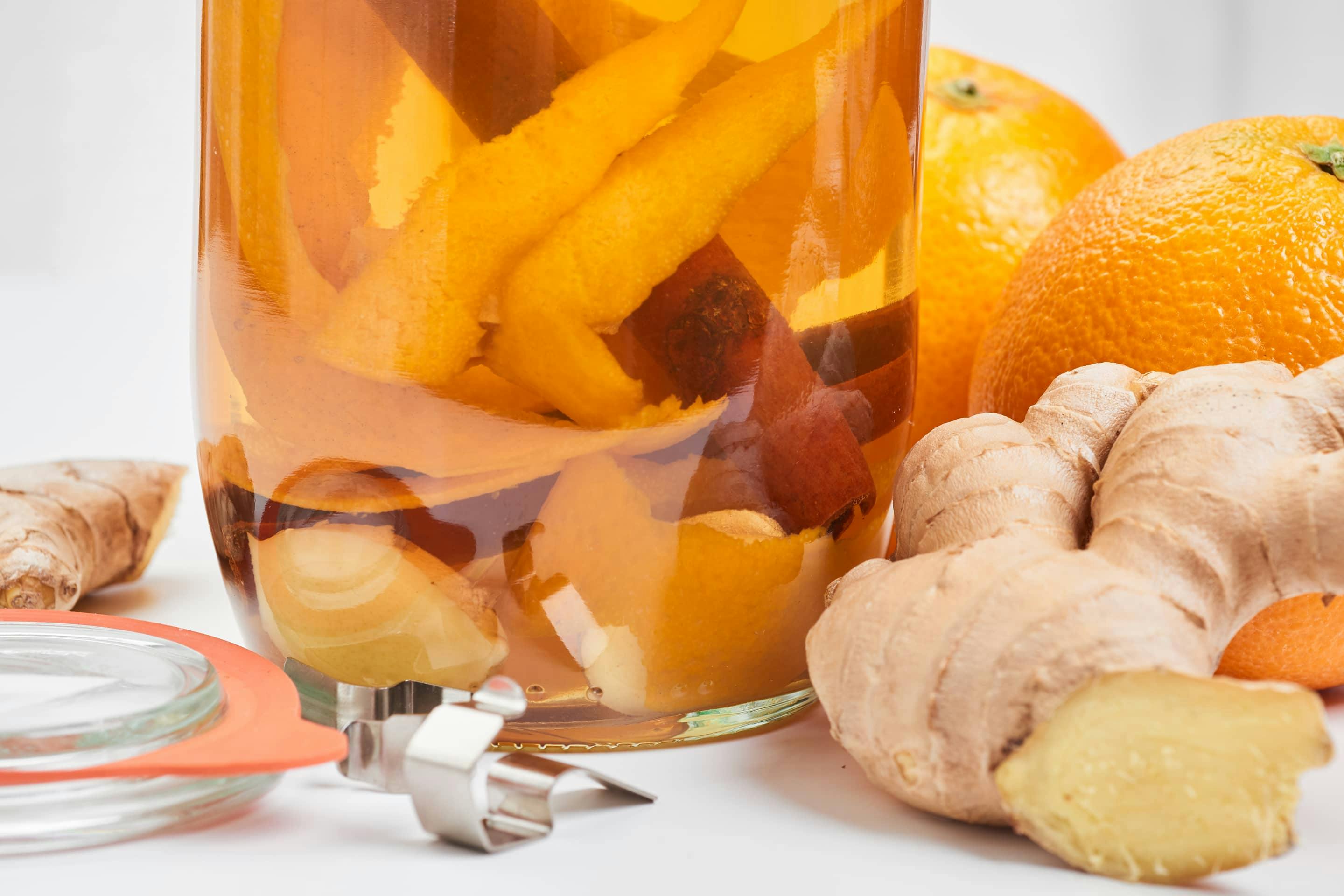 Orangen-Ingwer Essig in einer Flasche mit Orangenschalen und Ingwerscheiben