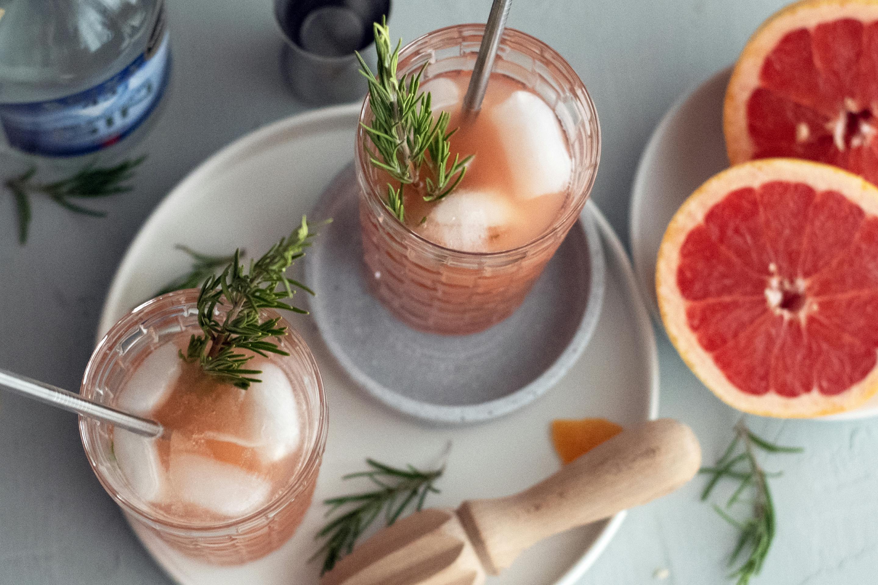 Gin Getränk im Glas mit Rosmarinzweig, Grapefruit und Strohhalm