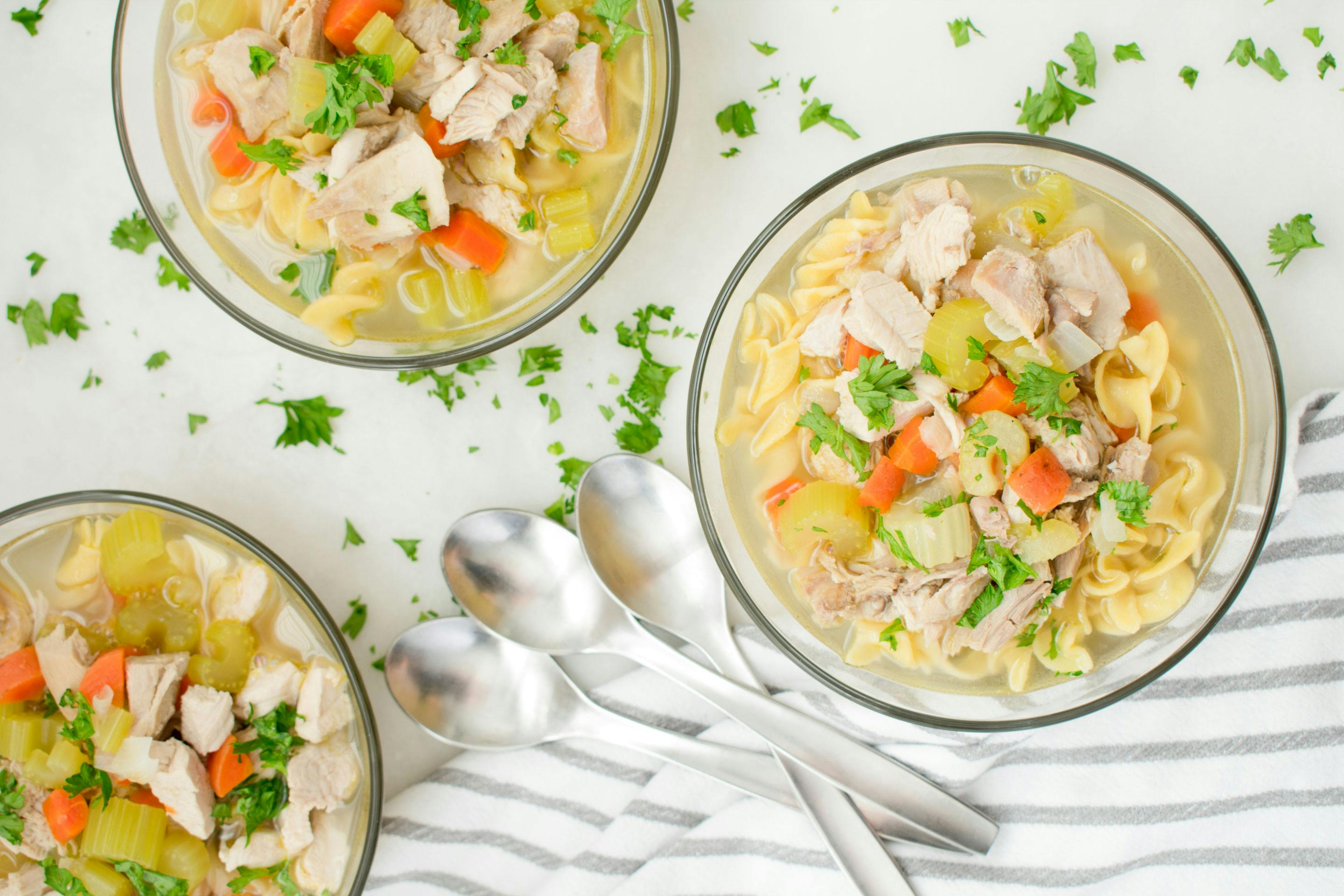 3 Teller mit Hühnersuppe mit Karotten, Nudeln und Sellerie