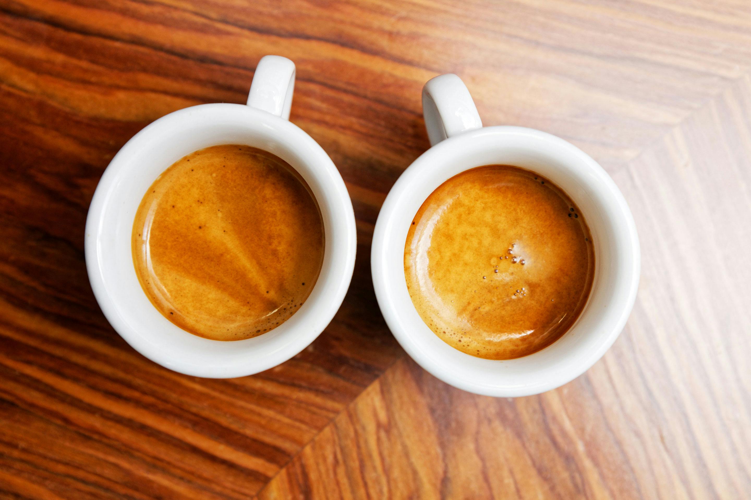 2 Tassen mit Espresso und Crema auf einem Holz-Untergrund