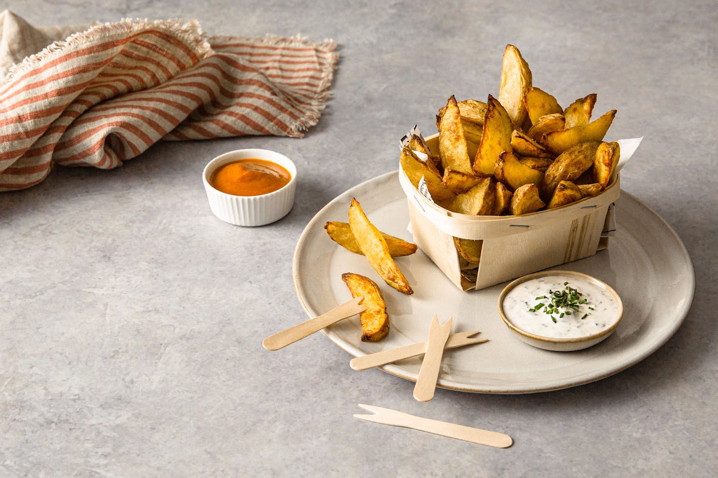 Crunchy Potato Wedges Mit Dips in einem Holzkörbchen auf einem Teller serviert