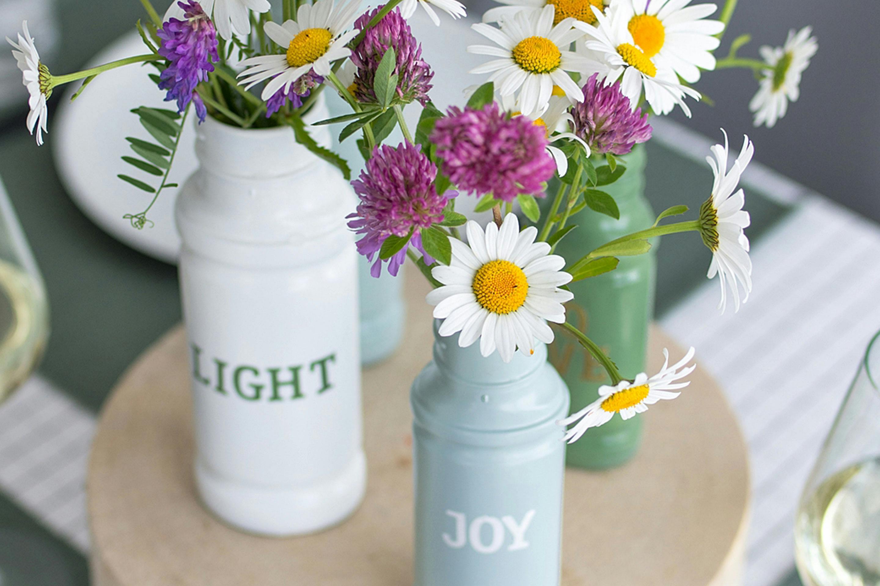 die fertigen DIY-Gewürzglas-Vasen mit frischen Wiesenblumen