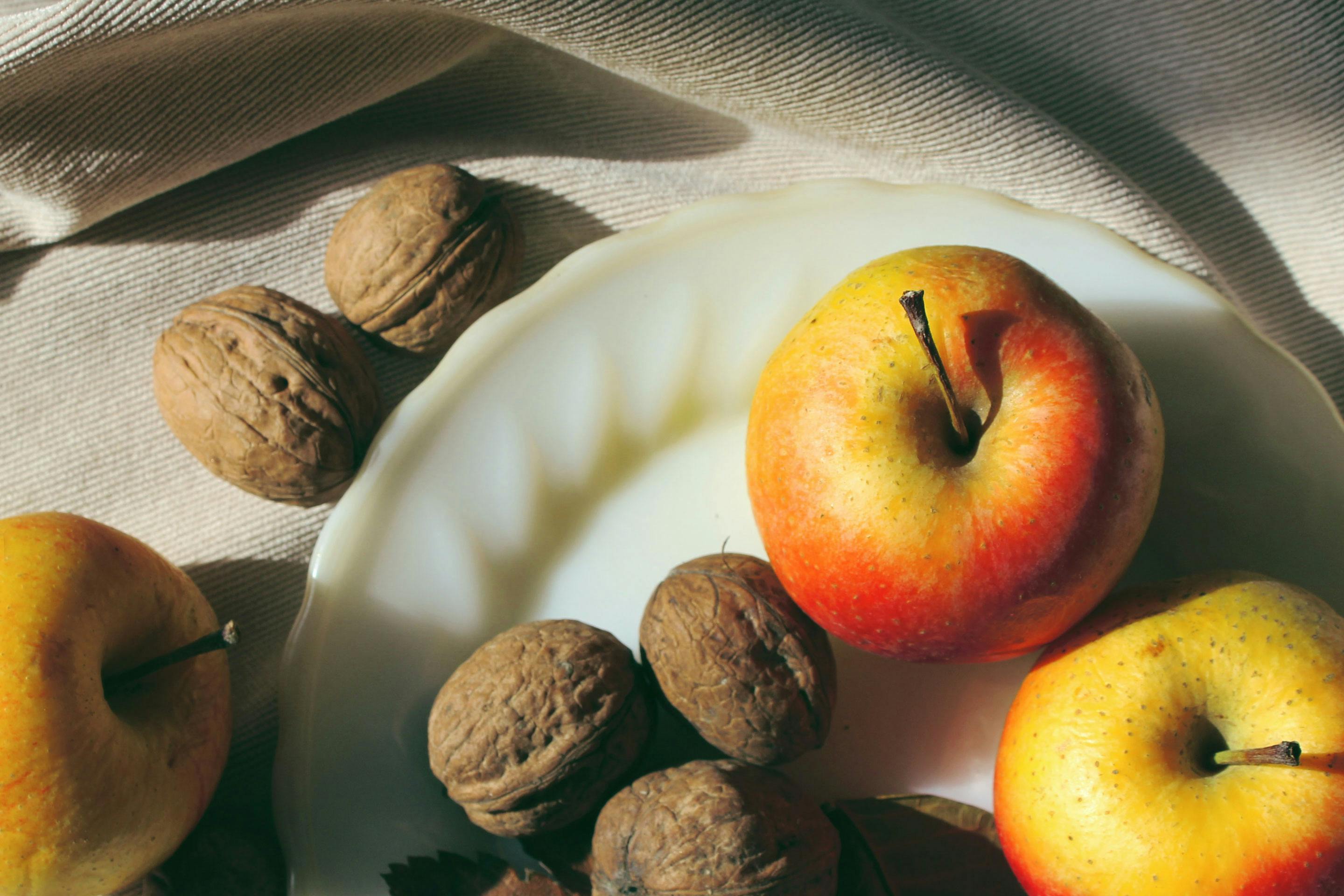 Äpfel und Walnüsse auf einem weißen Teller