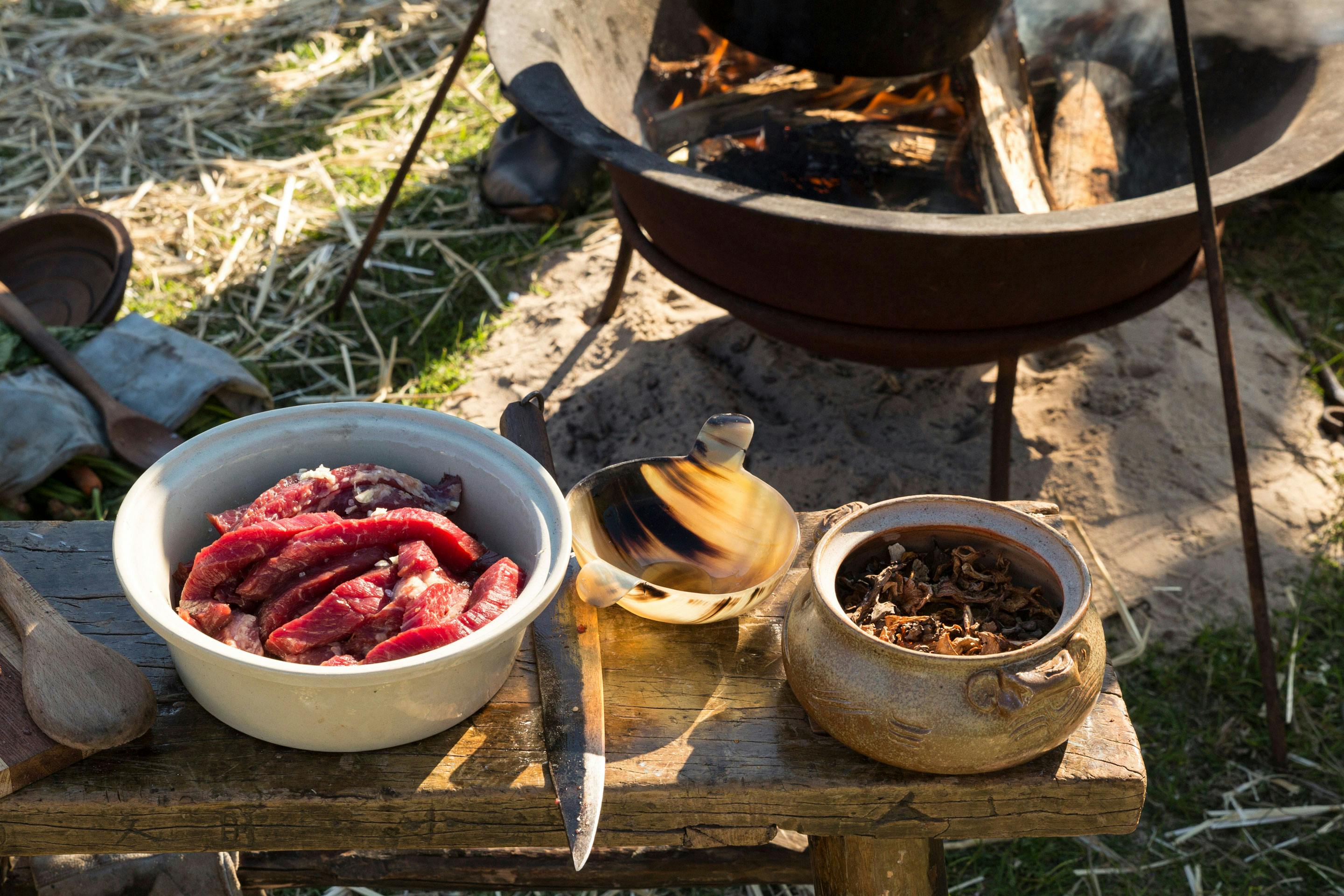 Mittelalterliche Feuerstelle mit Kessel und und einem Bänkchen mit Fleisch und Küchenwerzeug