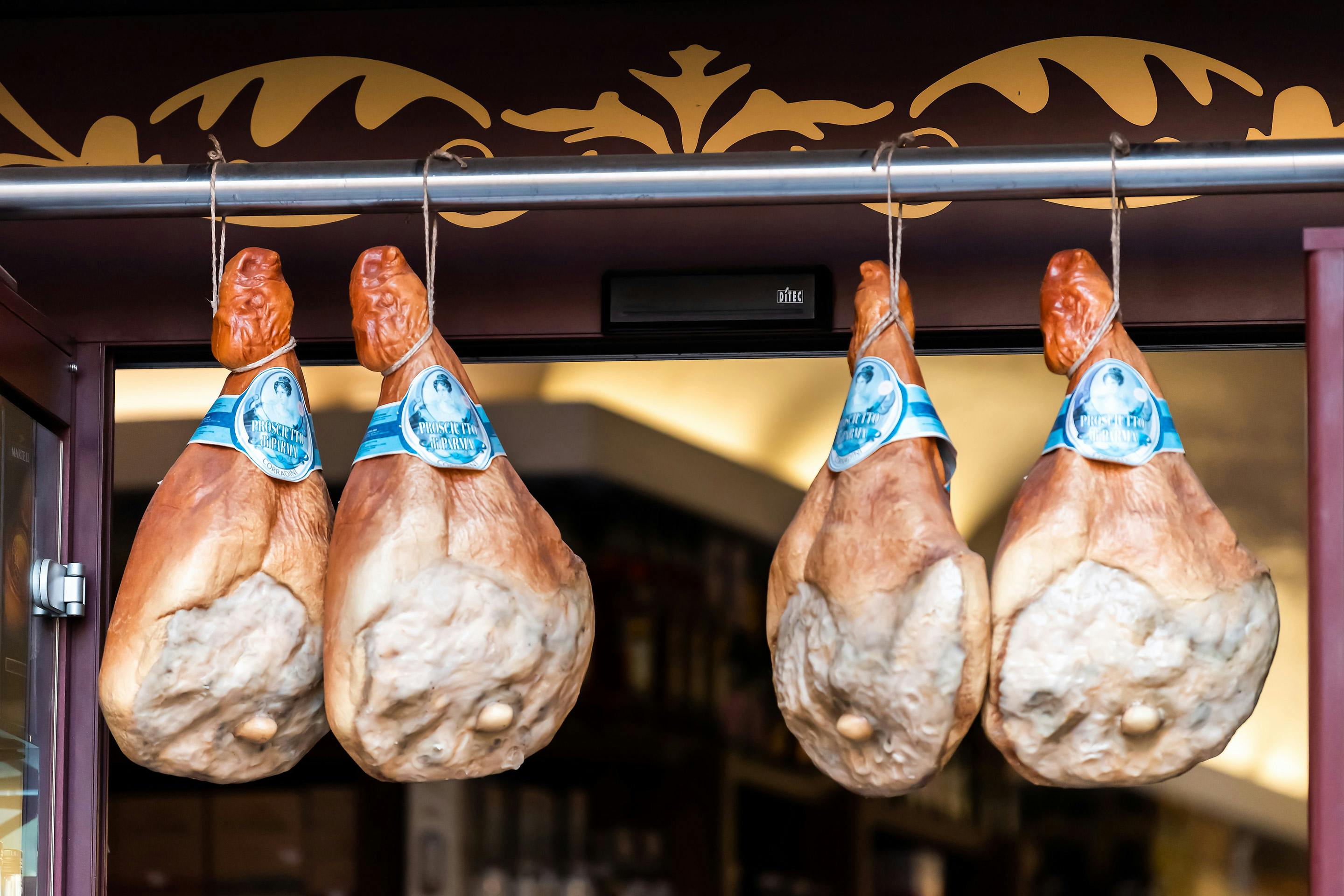 4 geräucherte und gepökelte Schweineschinken hängen vor einem italienischen Laden