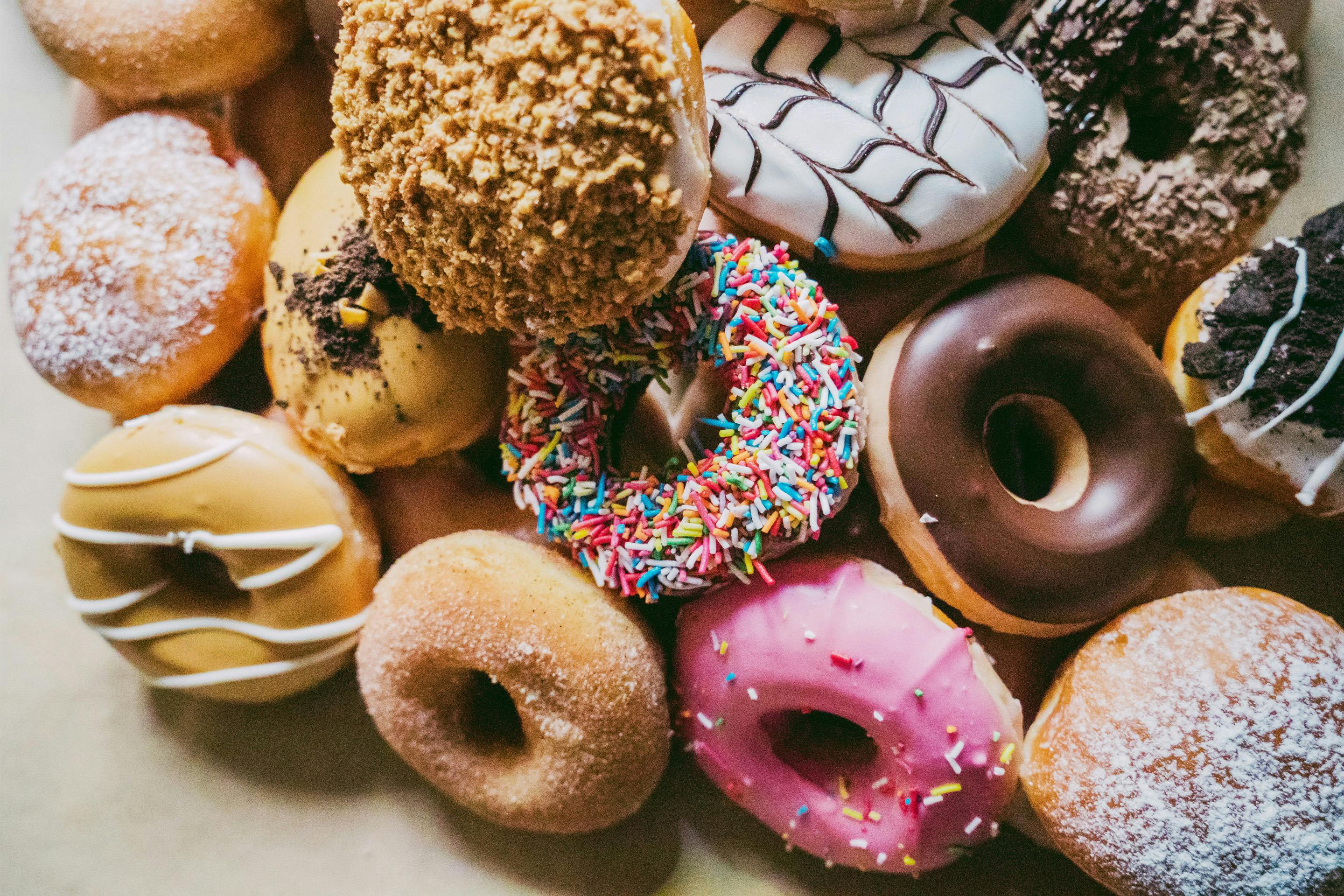 Eine Vielzahl an bunt bestreuten Donuts neben- und übereinander