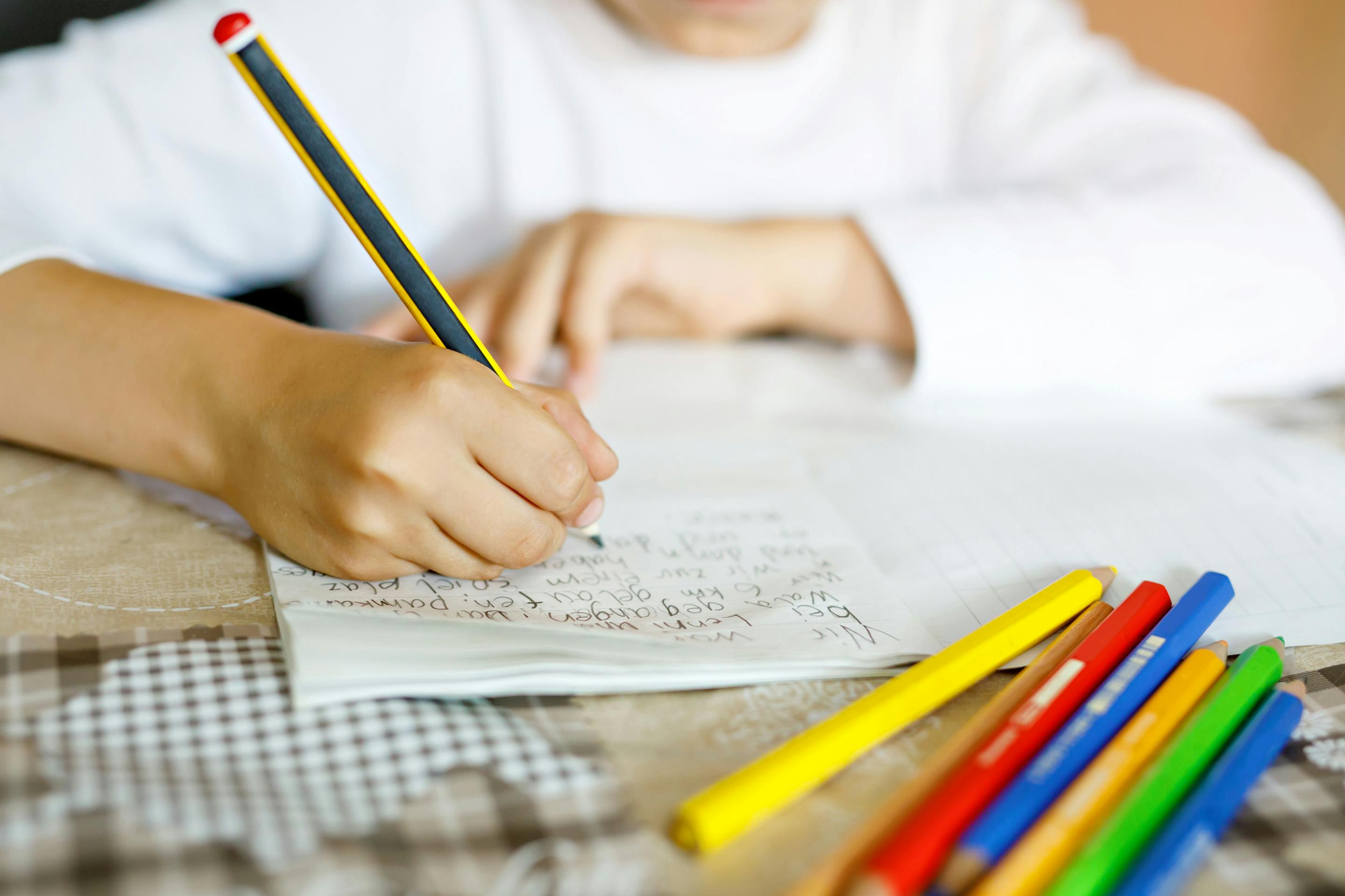 ein Kind schreibt im Unterricht in ein Heft