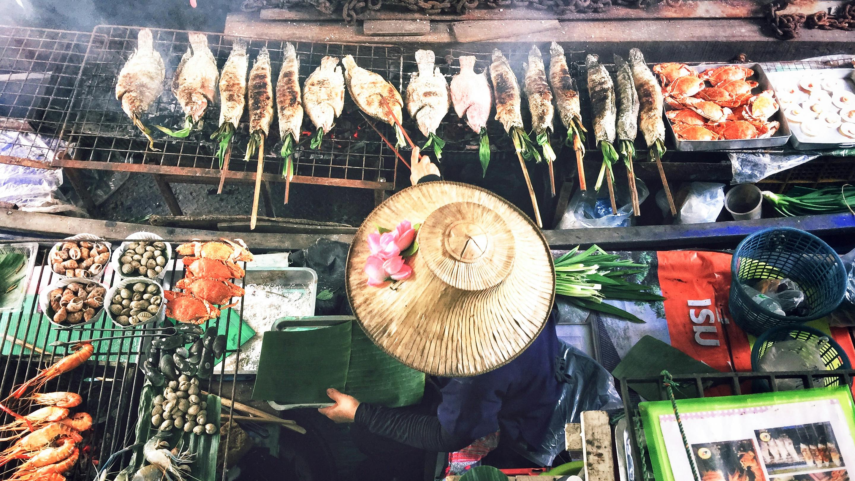 eine thailändische Köchin bereitet Gerichte in ihrem Boot auf den Klongs zu