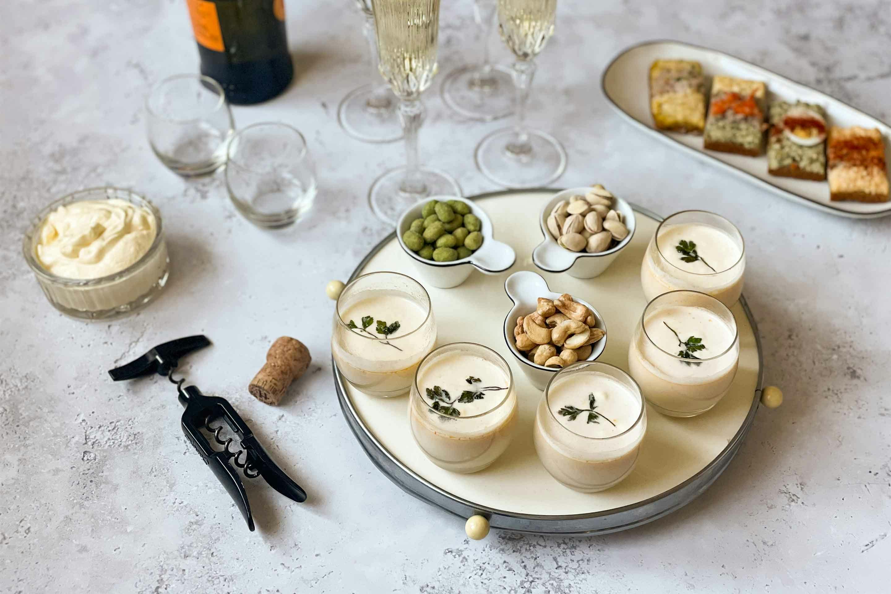 Ein festlicher Tisch mit Vorspeisen und Snacks – in der Mitte kleine Schalen mit Prosecco–Schaumsuppe.